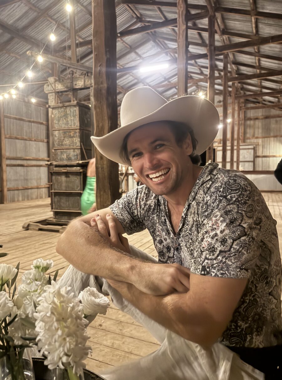 Matty Teague in a hat at a country woolshed table